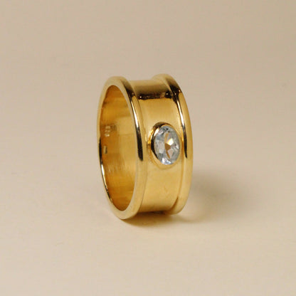 Gold ring with a gemstone on a beige background