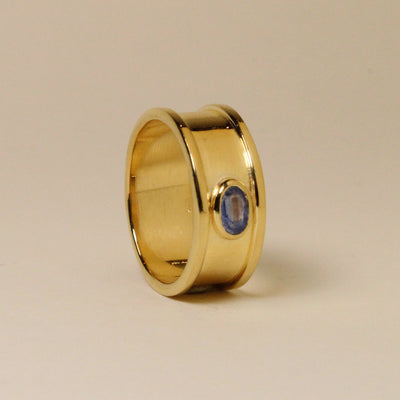 Gold ring with a blue gemstone on a beige background