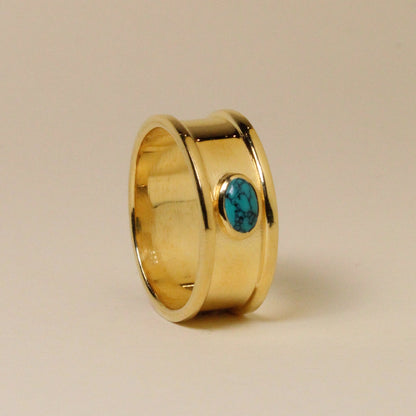 Gold ring with a turquoise stone on a beige background