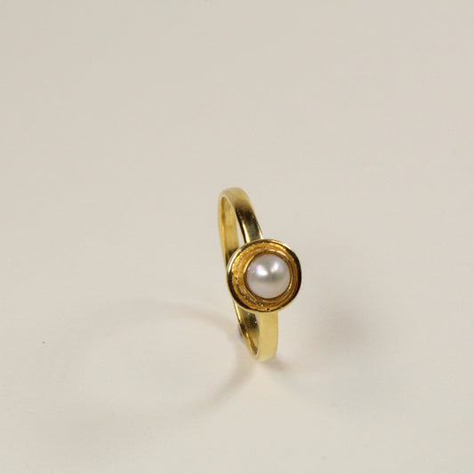 Gold ring with a pearl on a beige background